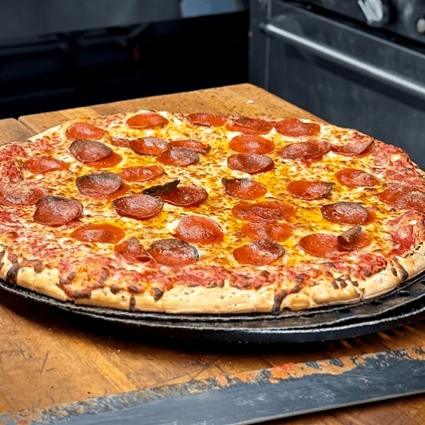 A freshly baked pepperoni pizza, golden brown and bubbling, rests on a wooden surface.