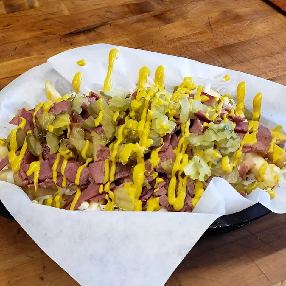 Pizza Chalet's pastrami fries, topped with sliced pastrami, pickles, and mustard drizzle.