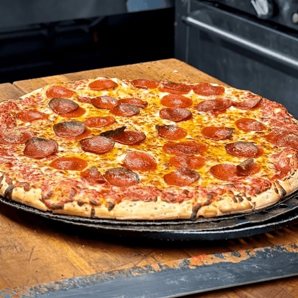 A freshly baked pepperoni pizza with melted cheese and crispy crust on a wooden surface.