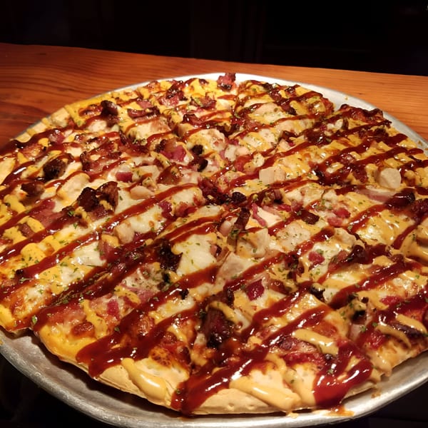 Pizza Chalet's BBQ chicken pizza, drizzled with barbecue sauce and a creamy yellow sauce.